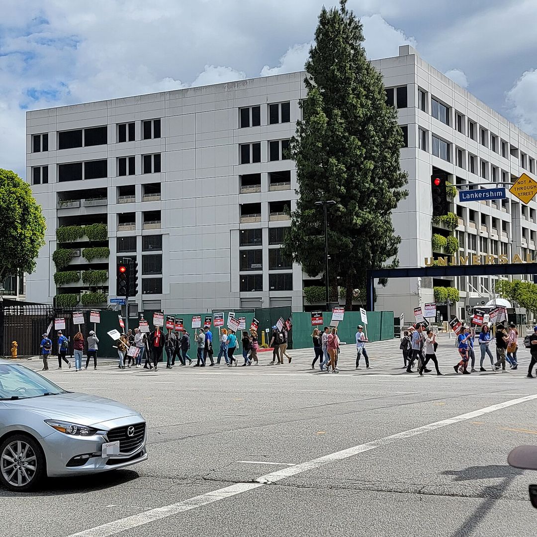 Scénaristes et soutiens en grève avec des pancartes devant une entrée des studios Universal.