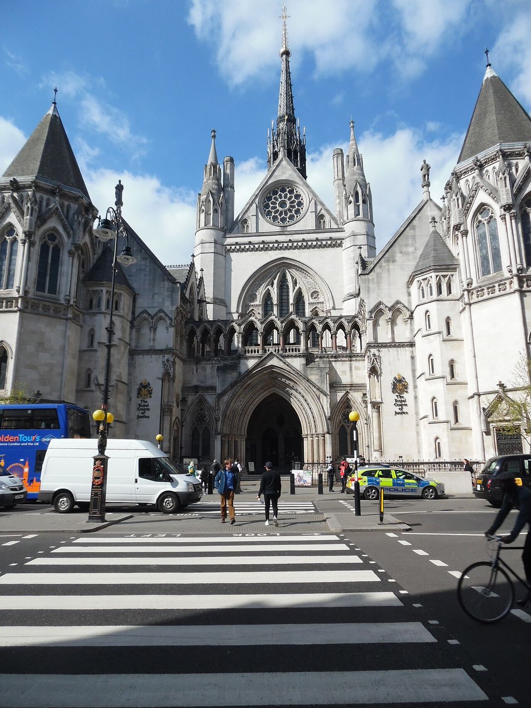 Façade néogothique des Royal Courts of Justice sur le Strand à Londres, avec un passage piéton au premier plan.