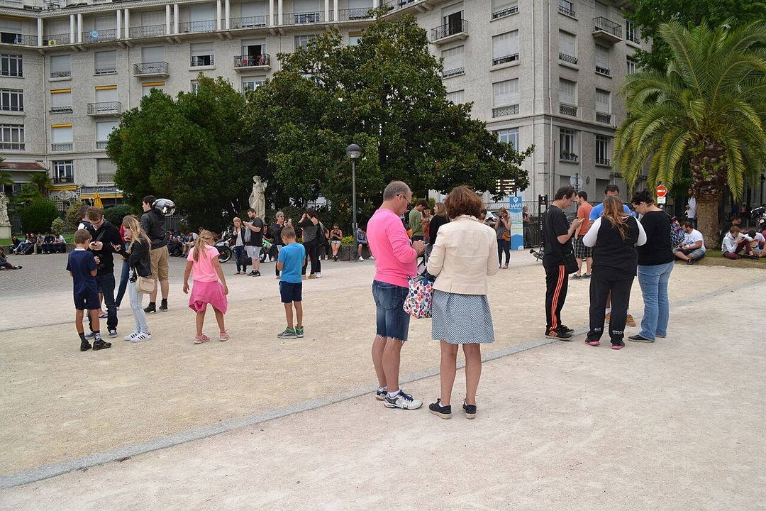 Groupe de joueurs regardant leur téléphone dans un square.
